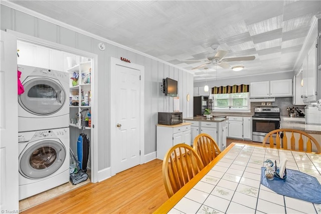 kitchen with white cabinetry, stacked washer / dryer, stainless steel range with electric cooktop, and ornamental molding