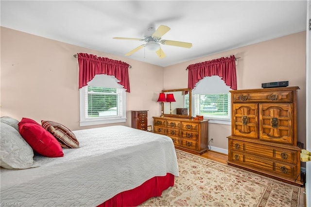 bedroom with multiple windows, wood-type flooring, and ceiling fan