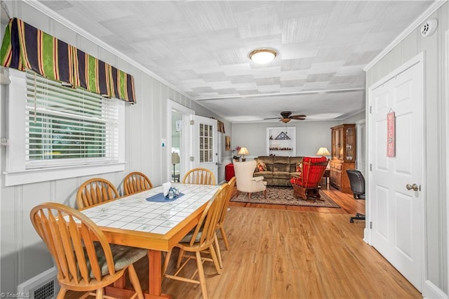 dining space with light hardwood / wood-style flooring, ceiling fan, and crown molding