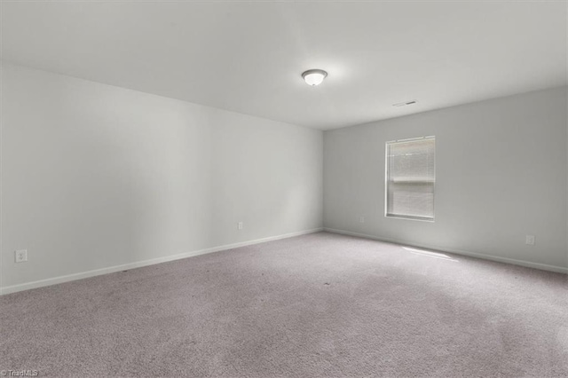carpeted empty room featuring baseboards