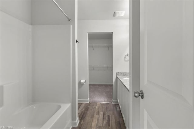 bathroom featuring baseboards, a spacious closet, wood finished floors, and vanity