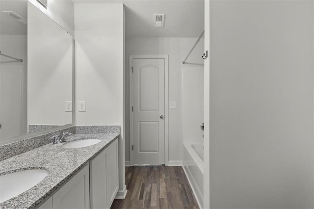 full bath featuring shower / tub combination, a sink, double vanity, visible vents, and wood finished floors