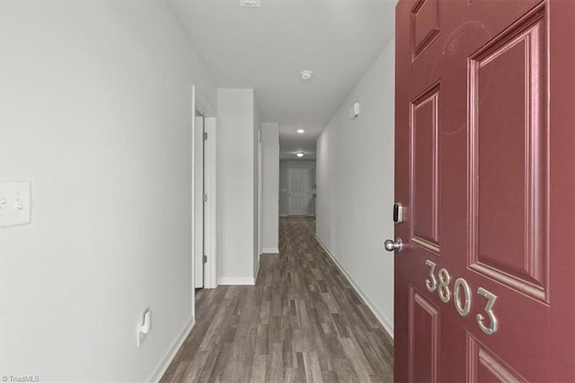 hallway featuring dark wood-style flooring and baseboards