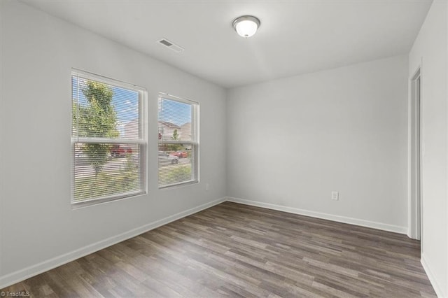 unfurnished room featuring wood finished floors, visible vents, and baseboards