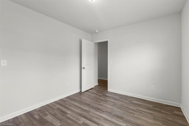 spare room featuring dark wood-style floors and baseboards