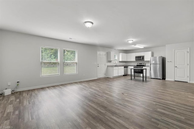 unfurnished living room featuring dark wood finished floors and baseboards