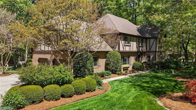 english style home with a front yard and brick siding
