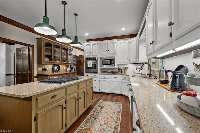 kitchen featuring recessed lighting, a sink, stainless steel appliances, a center island, and light stone counters