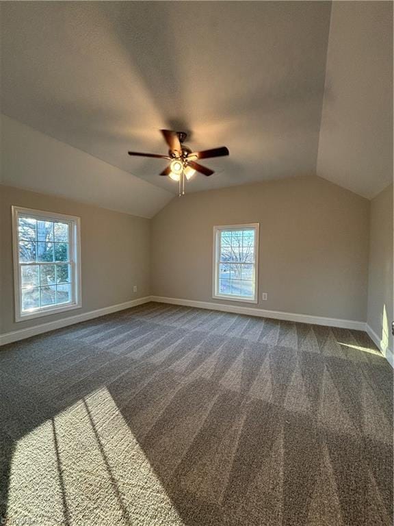 bonus room with dark colored carpet, vaulted ceiling, a wealth of natural light, and ceiling fan