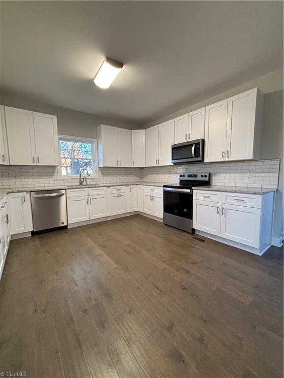 kitchen with backsplash, dark wood-type flooring, white cabinets, and stainless steel appliances