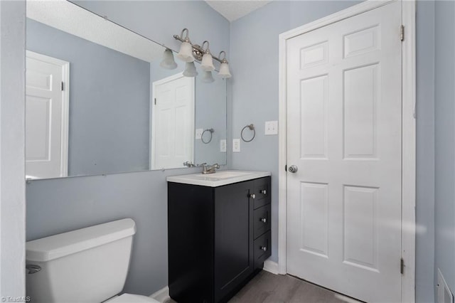 bathroom with hardwood / wood-style floors, vanity, and toilet