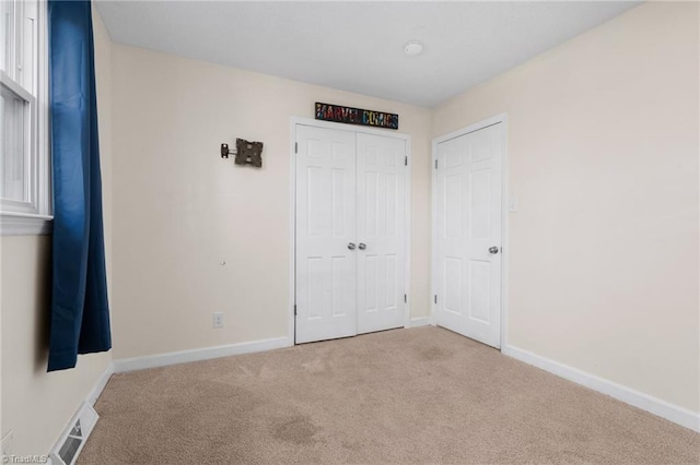 unfurnished bedroom featuring a closet and light colored carpet