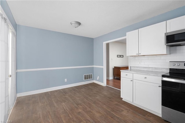 kitchen featuring backsplash, stainless steel appliances, white cabinetry, and dark hardwood / wood-style floors