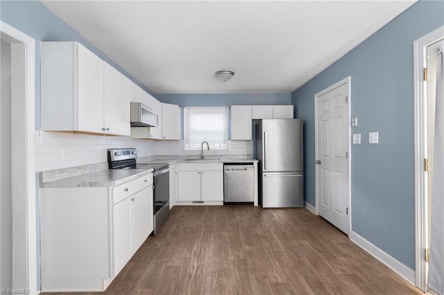 kitchen with hardwood / wood-style flooring, sink, white cabinets, and appliances with stainless steel finishes