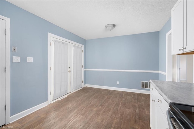 unfurnished dining area with dark hardwood / wood-style flooring and a textured ceiling