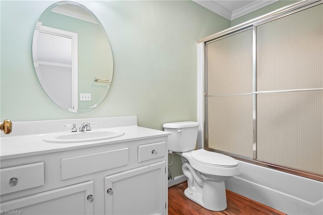 bathroom with crown molding, bath / shower combo with glass door, toilet, wood finished floors, and vanity