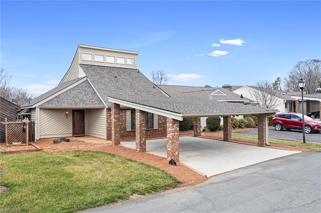 view of front facade with a carport, a shingled roof, a front lawn, and brick siding