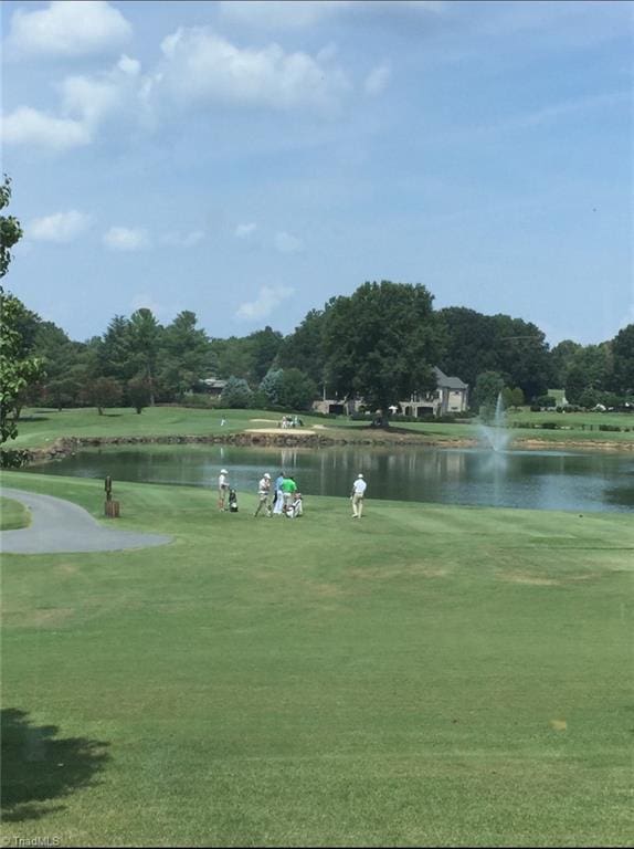 view of home's community featuring a lawn, view of golf course, and a water view