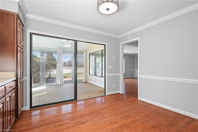 unfurnished room featuring light wood-style floors, baseboards, and ornamental molding