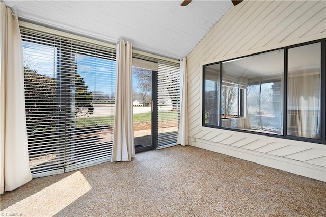 unfurnished sunroom with a ceiling fan and vaulted ceiling