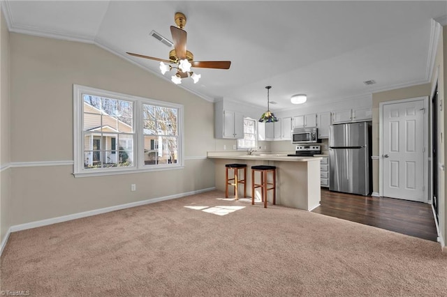 kitchen featuring stainless steel appliances, a peninsula, dark carpet, and visible vents