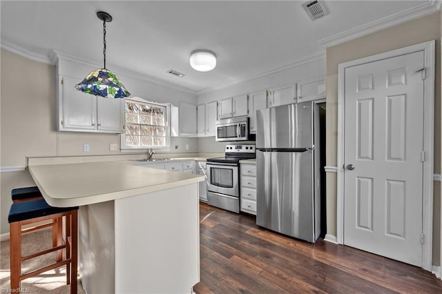 kitchen with visible vents, a peninsula, stainless steel appliances, and crown molding