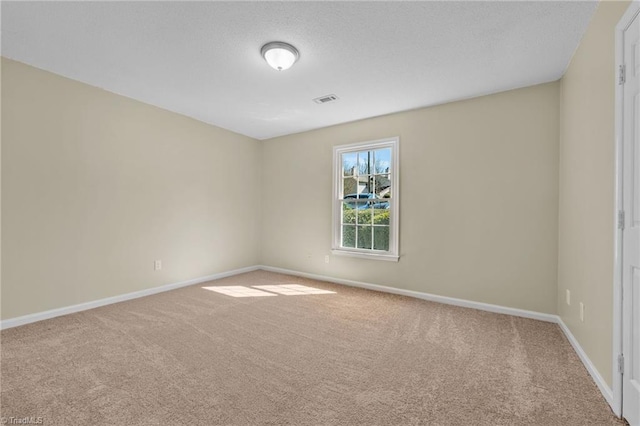 unfurnished room with visible vents, baseboards, carpet, and a textured ceiling