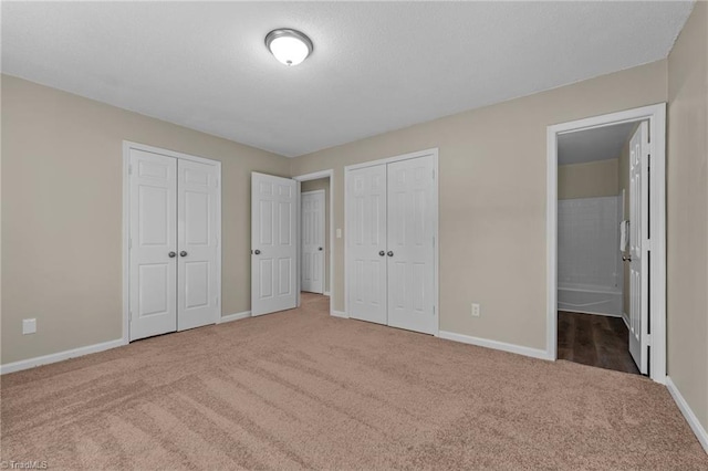 unfurnished bedroom with baseboards, multiple closets, and carpet floors