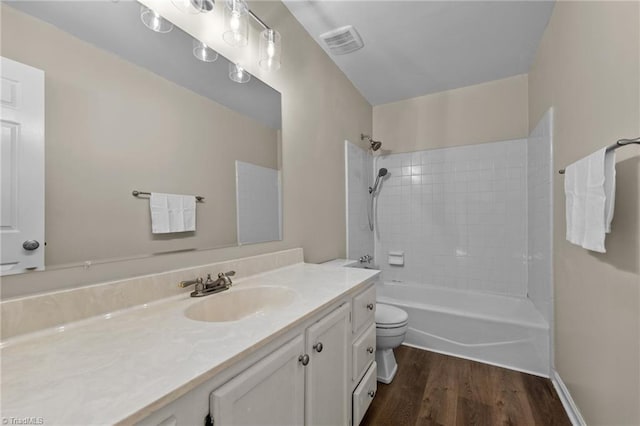 bathroom featuring vanity, wood finished floors, visible vents, shower / washtub combination, and toilet