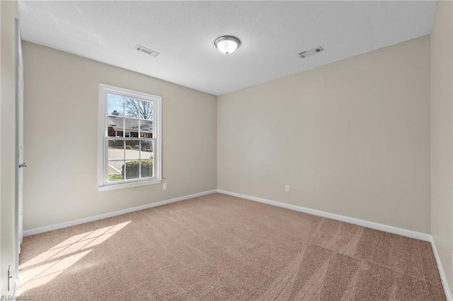 empty room featuring visible vents, baseboards, and carpet