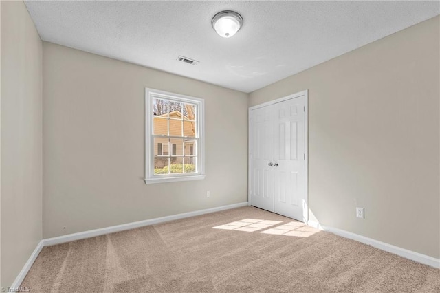 unfurnished bedroom with visible vents, baseboards, a closet, and carpet flooring