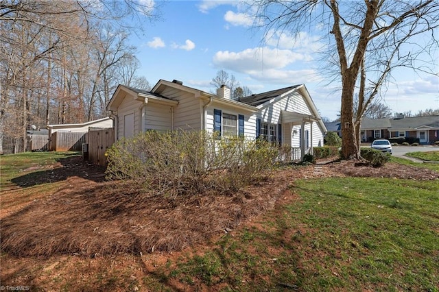 view of property exterior with a lawn, a chimney, and fence