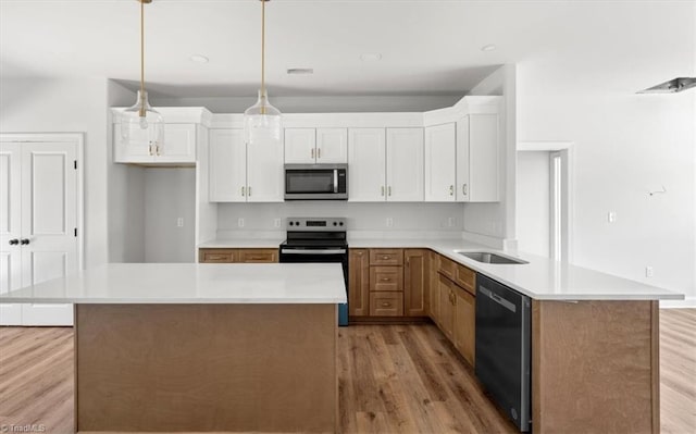 kitchen featuring a kitchen island, white cabinetry, light hardwood / wood-style flooring, decorative light fixtures, and stainless steel appliances