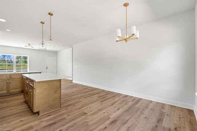 kitchen with an inviting chandelier, a kitchen island, decorative light fixtures, and light wood-type flooring