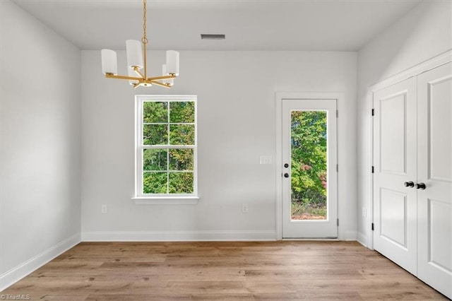 interior space with light hardwood / wood-style floors, a healthy amount of sunlight, and a chandelier