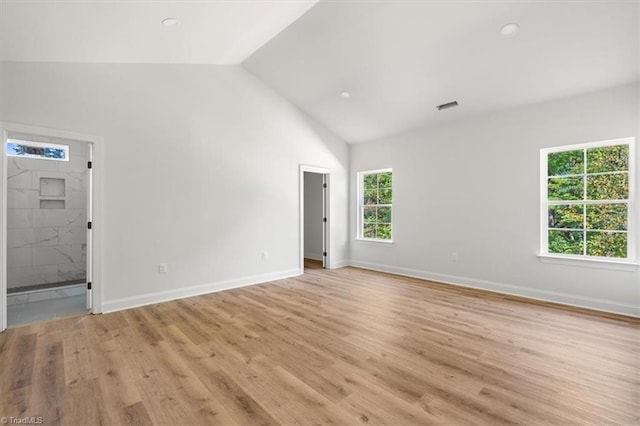 spare room featuring lofted ceiling and light wood-type flooring