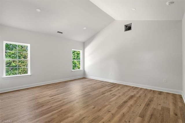 spare room with light hardwood / wood-style flooring and lofted ceiling