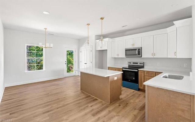 kitchen with stainless steel appliances, pendant lighting, a kitchen island, and white cabinets