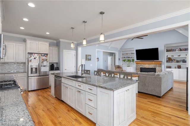 kitchen with stainless steel appliances, white cabinetry, sink, and light stone counters