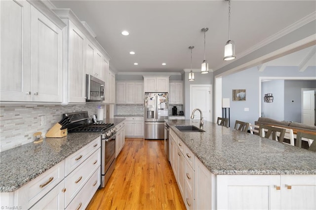 kitchen with white cabinets, appliances with stainless steel finishes, sink, and a large island with sink