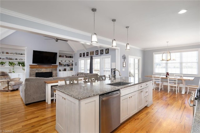 kitchen featuring white cabinetry, sink, a kitchen island with sink, stainless steel dishwasher, and light stone countertops