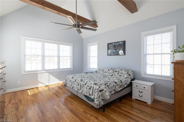 bedroom with ceiling fan, hardwood / wood-style floors, and vaulted ceiling with beams