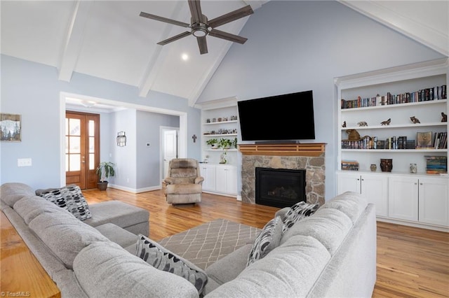 living room featuring a stone fireplace, built in features, high vaulted ceiling, beamed ceiling, and light hardwood / wood-style floors