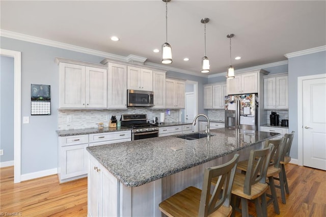 kitchen with sink, a breakfast bar area, white cabinetry, a kitchen island with sink, and stainless steel appliances