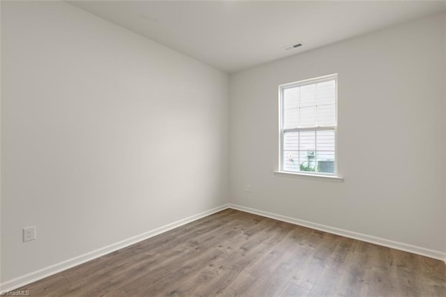 spare room featuring baseboards and wood finished floors