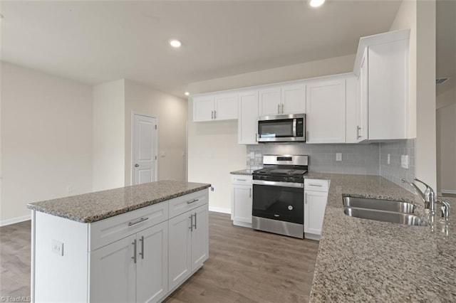 kitchen with light wood finished floors, decorative backsplash, stainless steel appliances, and a sink