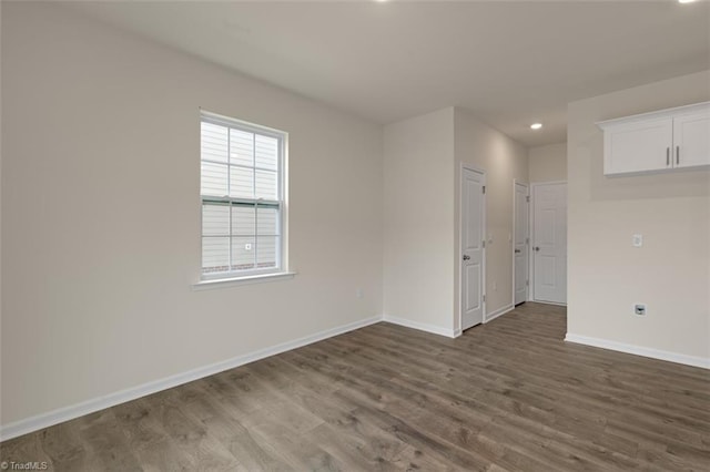 spare room featuring recessed lighting, dark wood finished floors, and baseboards