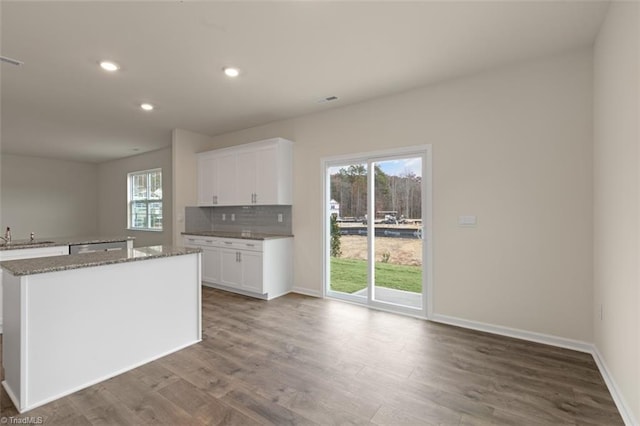 kitchen featuring stone countertops, recessed lighting, wood finished floors, white cabinets, and backsplash