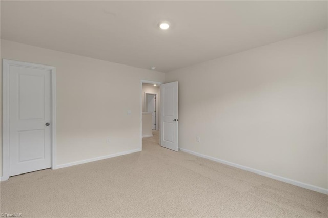 unfurnished room with light carpet and baseboards