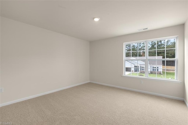 spare room with light colored carpet, visible vents, and baseboards